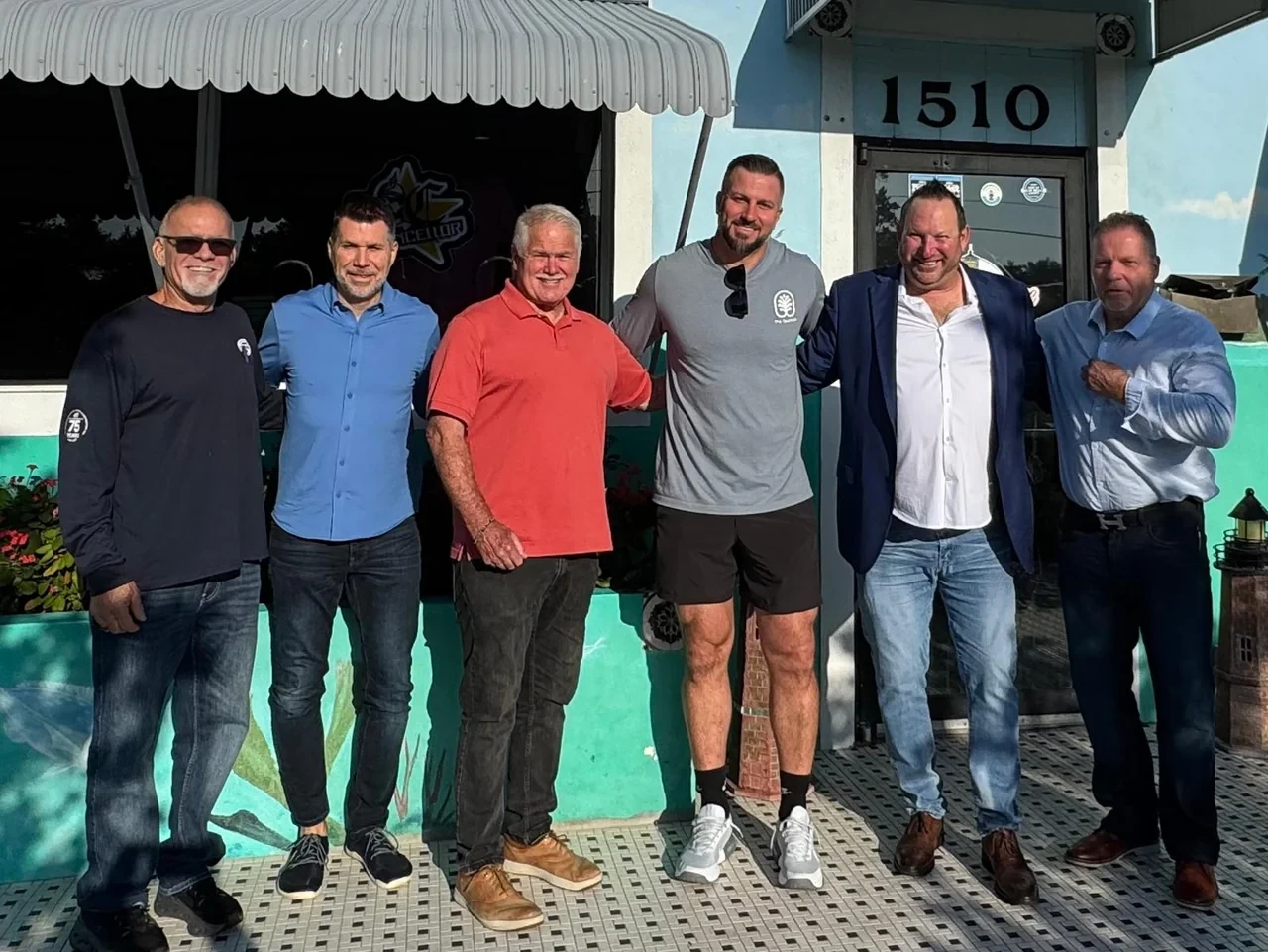 Michael Fineman with five men from his cohort, arm in arm outside a diner in the sun